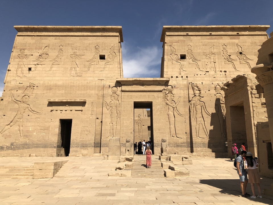 Des touristes entrant dans un ancien temple égyptien avec des sculptures.