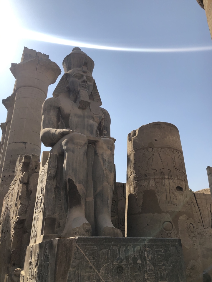 Grande statue antique et un pilier avec des hiéroglyphes.