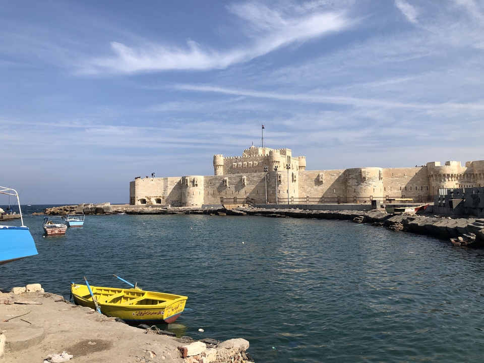 Forteresse de pierre au bord de la mer avec des bateaux dans l'eau.