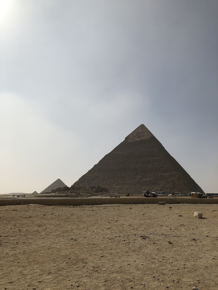 De grandes pyramides se dressent majestueusement sous un ciel brumeux.