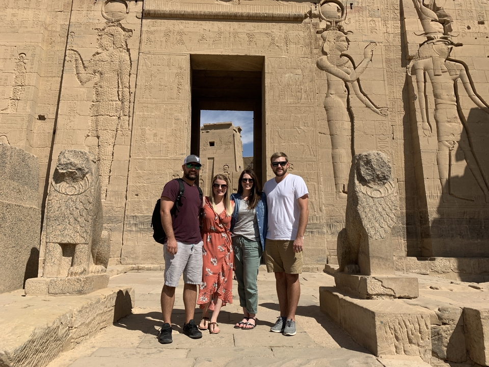 Groupe de quatre personnes debout devant des ruines de l'Égypte antique.
