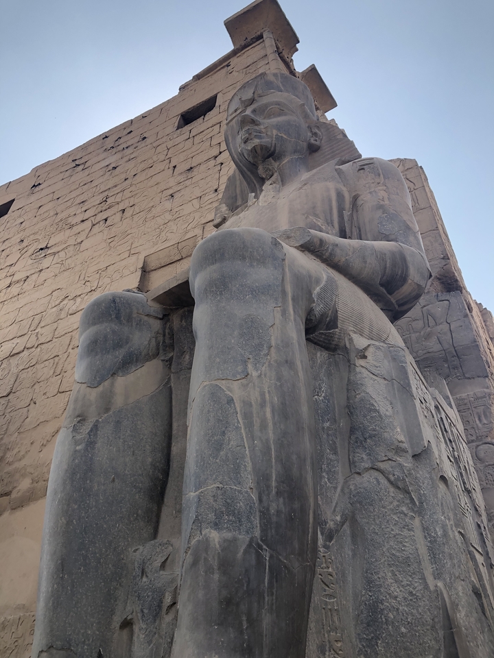 Vue en gros plan d'une grande statue de pierre avec deux jambes visibles.