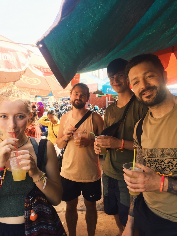 Groupe d'amis avec des boissons dans un marché animé.