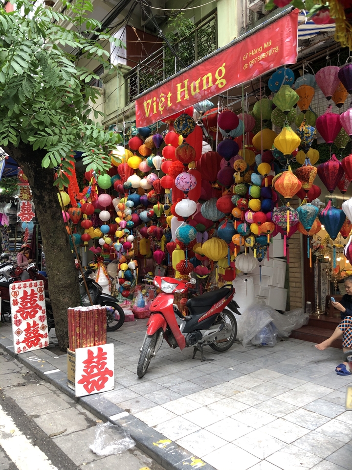 Rue décorée de lanternes colorées et de motos garées à proximité.