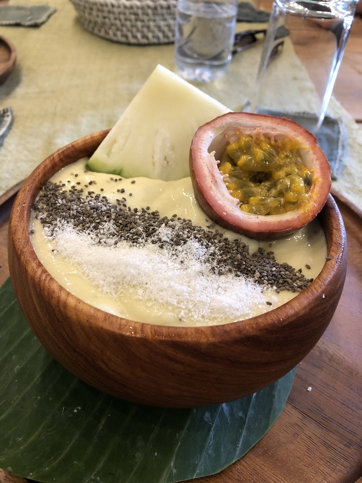 Un bol en bois avec un smoothie tropical et des garnitures de fruits.