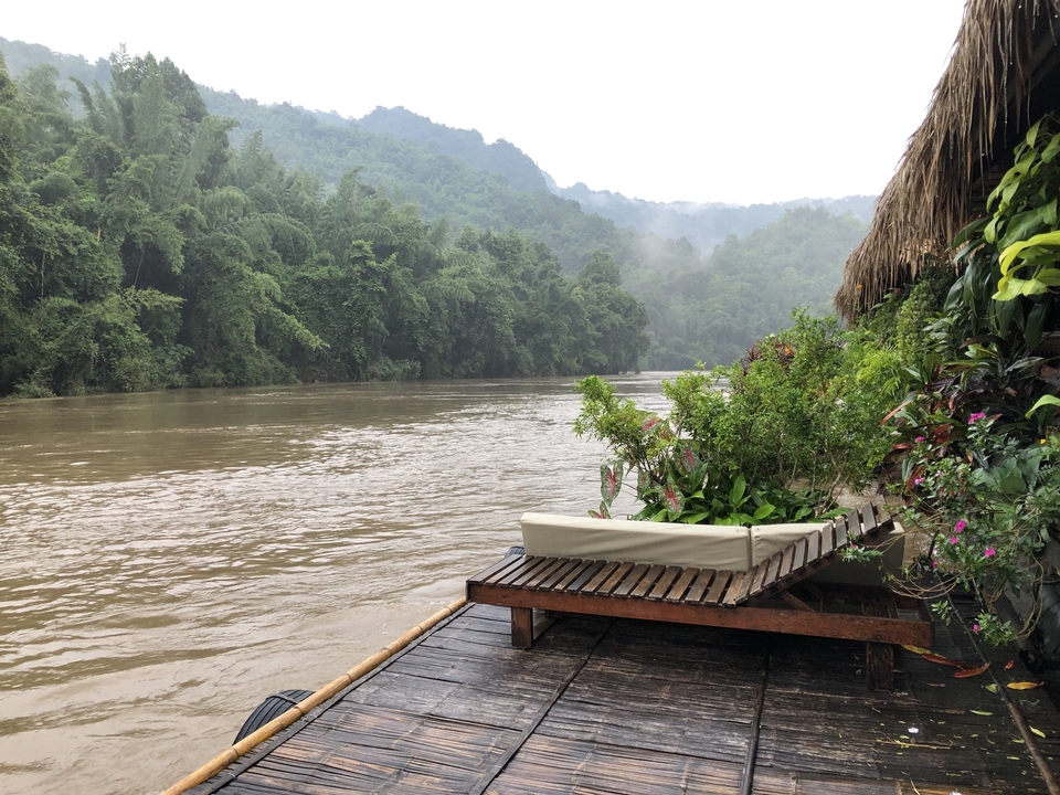 Vue paisible sur la rivière avec un environnement forestier luxuriant et une terrasse en bois.