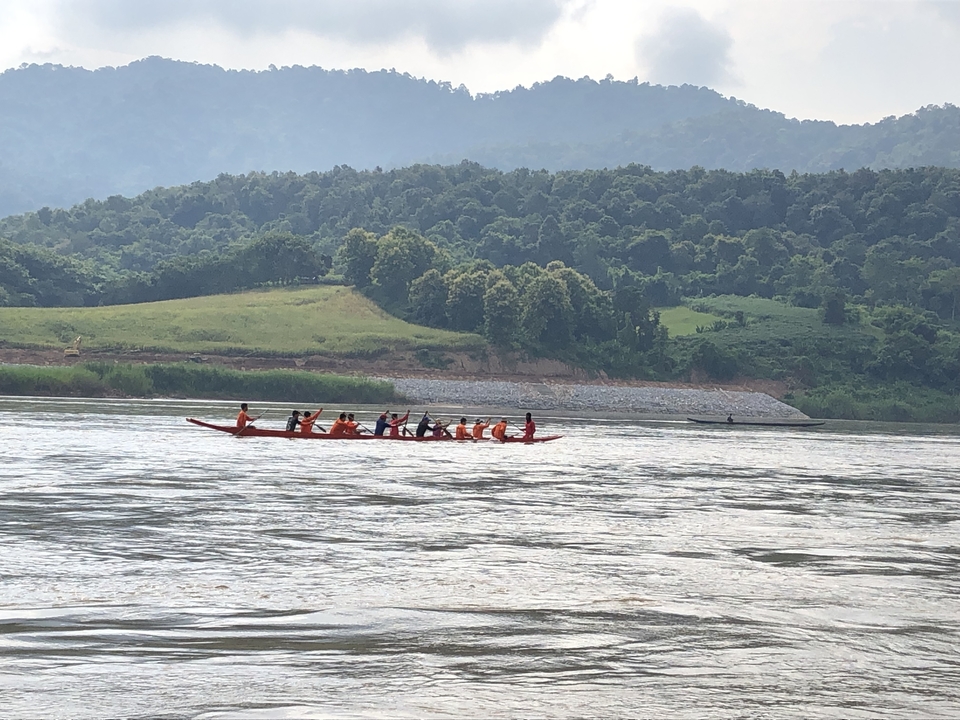 Groupe de personnes ramant dans une pirogue traditionnelle sur une rivière.