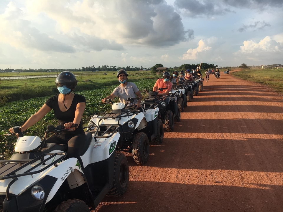 Groupe de personnes conduisant des quads sur un chemin de terre.