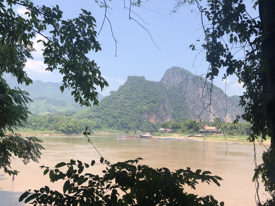 Vue panoramique d'une rivière avec des collines boisées en arrière-plan.