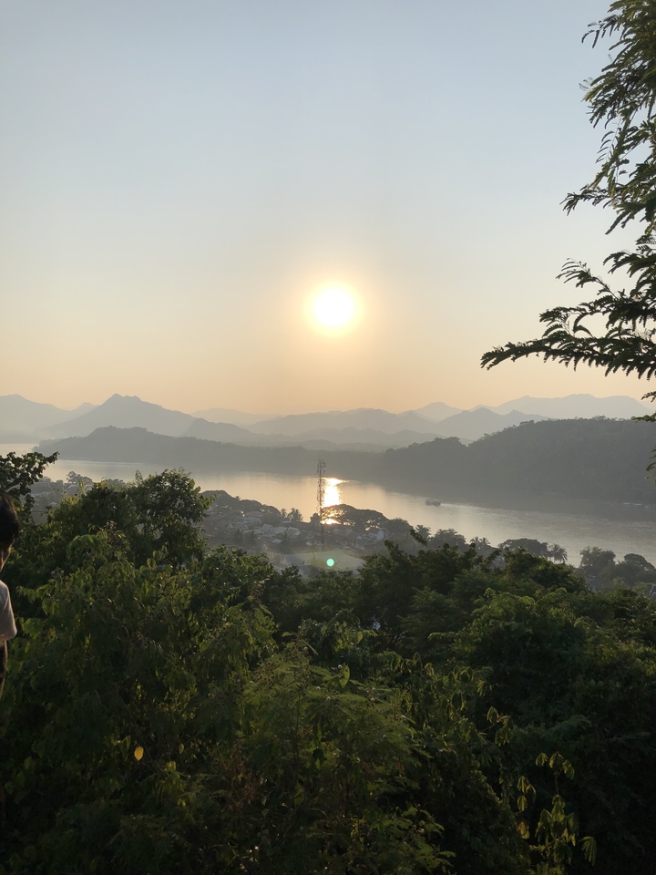 Une rivière avec un coucher de soleil se reflétant sur l'eau, entourée de collines.