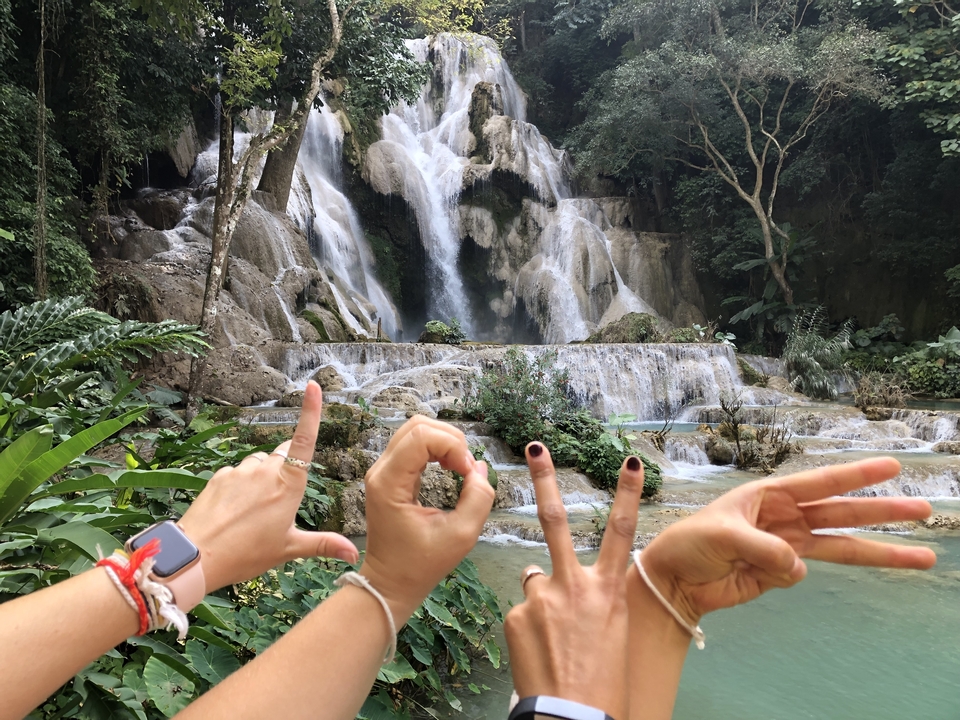 Femmes posant devant une cascade dans une forêt luxuriante.