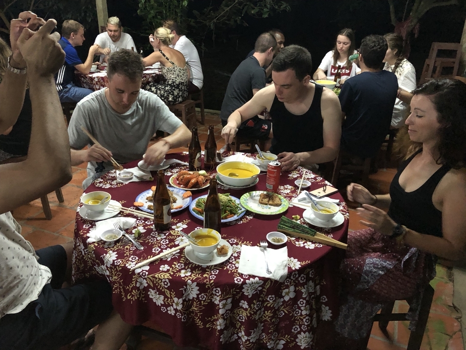 Un groupe de personnes qui dînent autour d'une table avec de la nourriture vietnamienne traditionnelle.