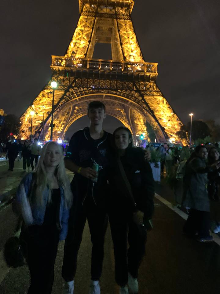 Groupe devant une structure illuminée la nuit.