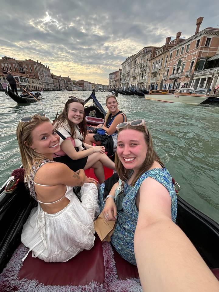 Quatre femmes lors d'une promenade en gondole dans une ville de canaux.