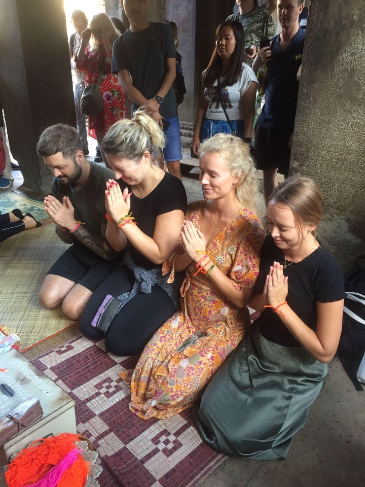 Quatre personnes assises en tailleur sur un tapis, en train de prier.