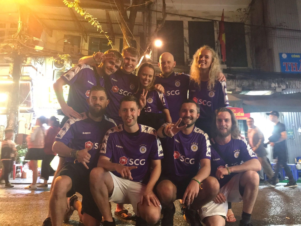 Photo de groupe de personnes en maillots de sport souriants la nuit.
