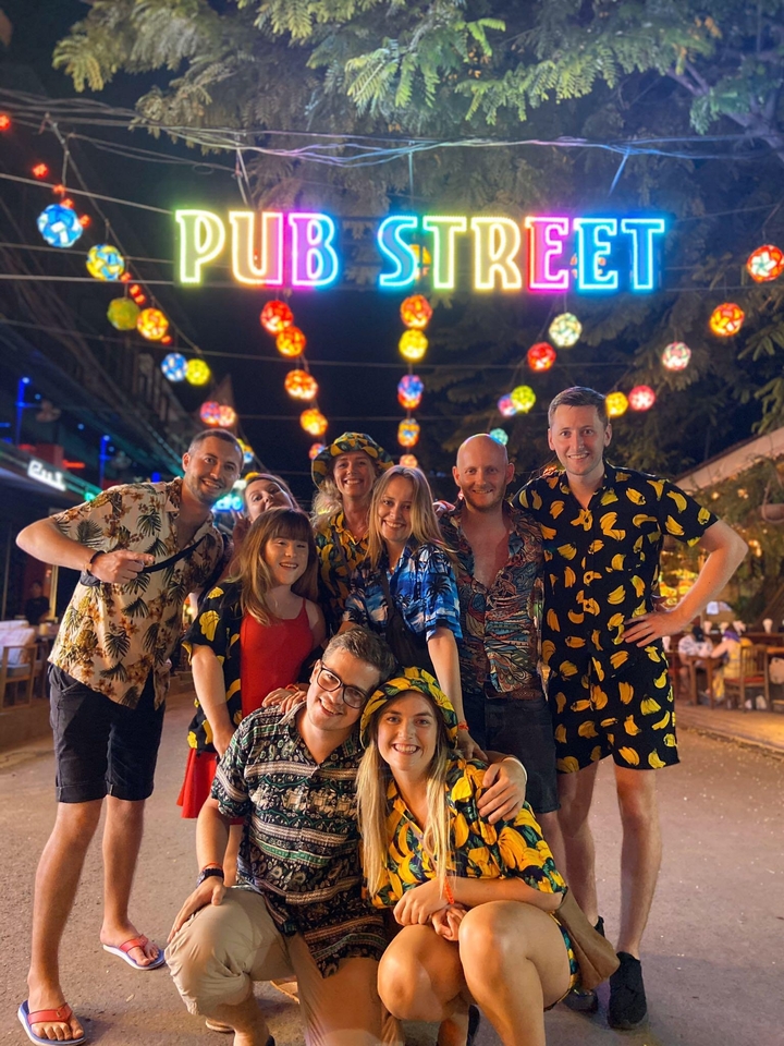 Groupe d'amis souriants dans un lieu animé décoré de lanternes suspendues la nuit.