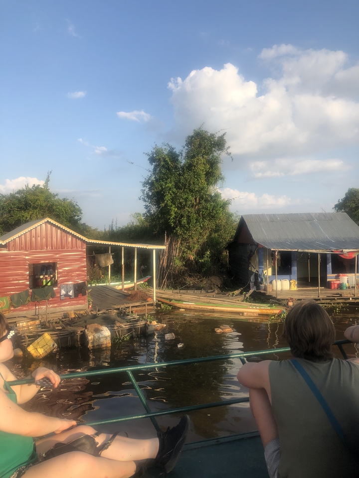 Homme travaillant sur une structure en bois au bord d'une rivière au coucher du soleil.