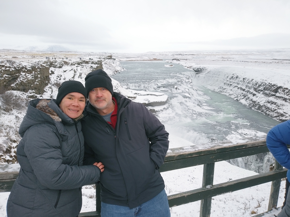 Couple posant à un point de vue sur une cascade enneigée.