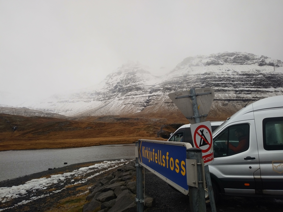 Panneau avec des montagnes en arrière-plan, indiquant un lieu appelé Hundafoss.