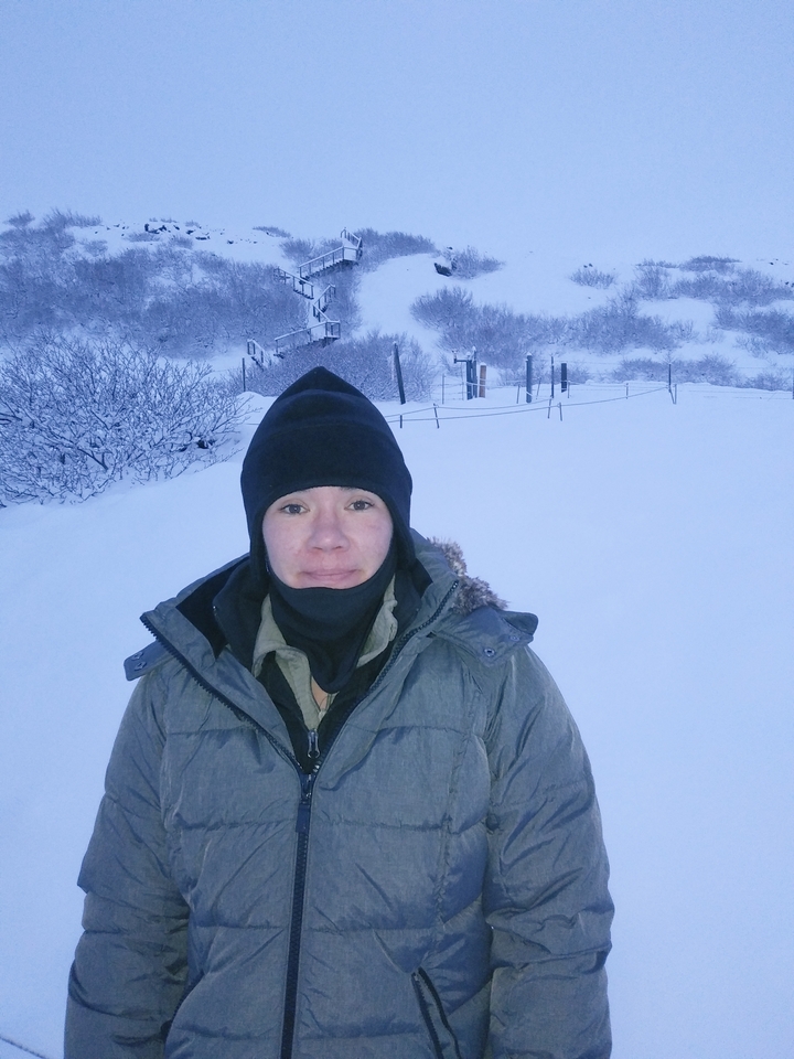 Personne en tenue d'hiver se tenant dans un paysage enneigé.