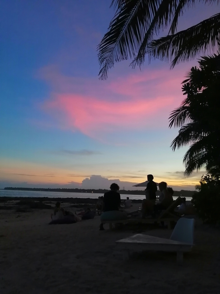 Des gens en silhouette contre un coucher de soleil coloré sur la plage.