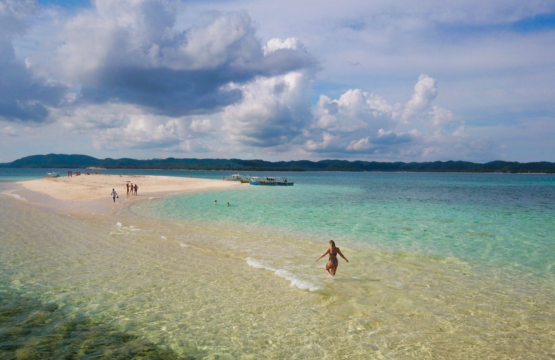 Des gens profitant d'un banc de sable avec de l'eau turquoise tout autour.