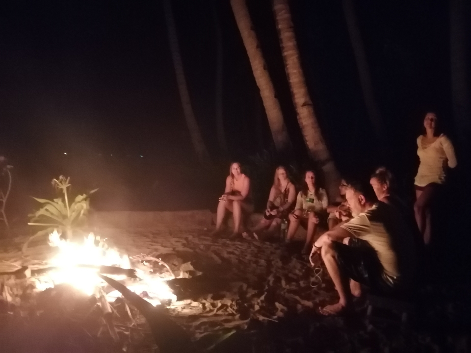 Des gens assis autour d'un feu de camp la nuit sur la plage.