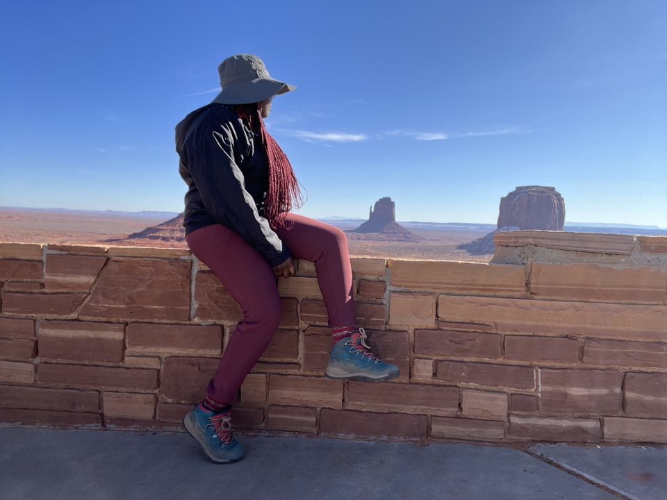Une personne assise sur un mur surplombant des formations désertiques.