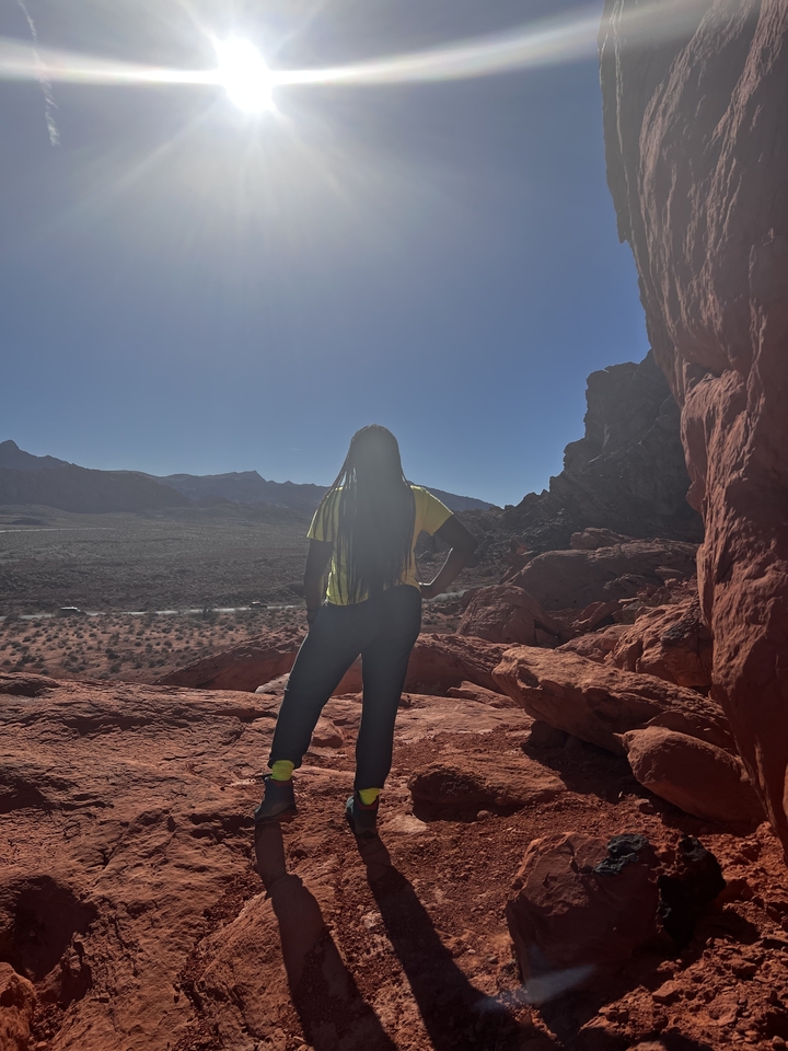 Une personne debout sur un terrain rocheux regardant vers le désert.