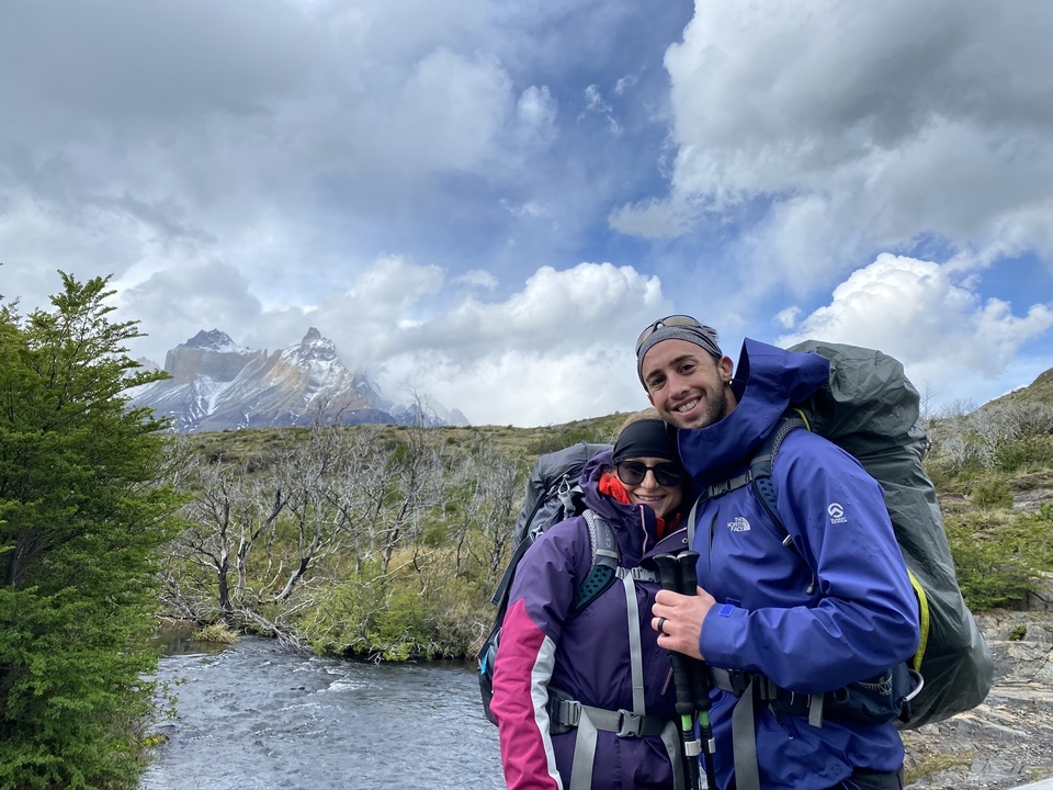 Deux randonneurs avec des sacs à dos posant devant des montagnes.