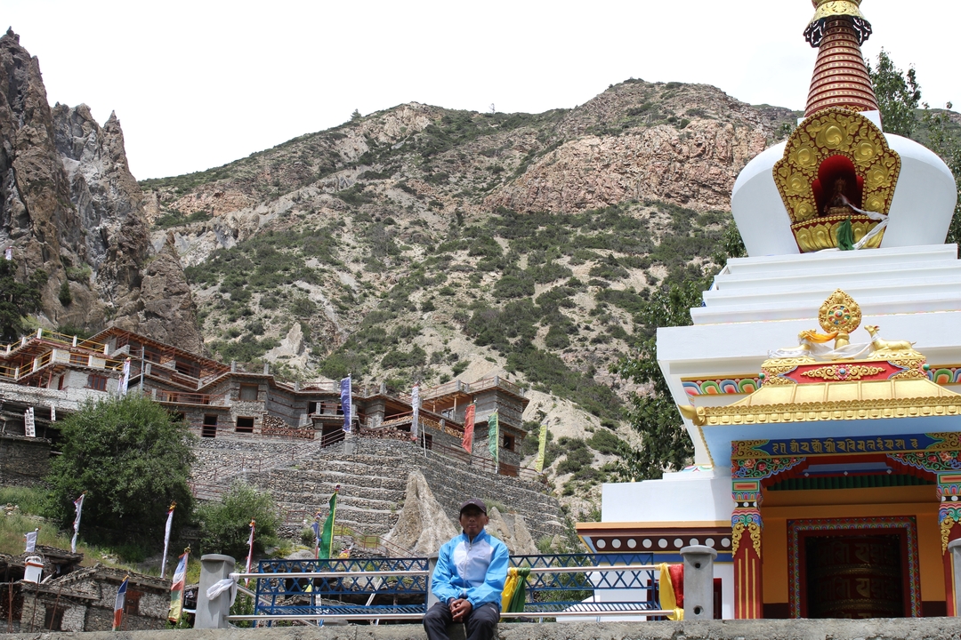 Colourful stupa and hillside village set against rocky mountains in Nepal.
