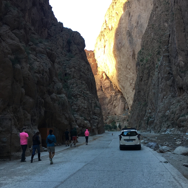 Des gens marchant à travers un canyon avec la lumière du soleil qui filtre à travers.