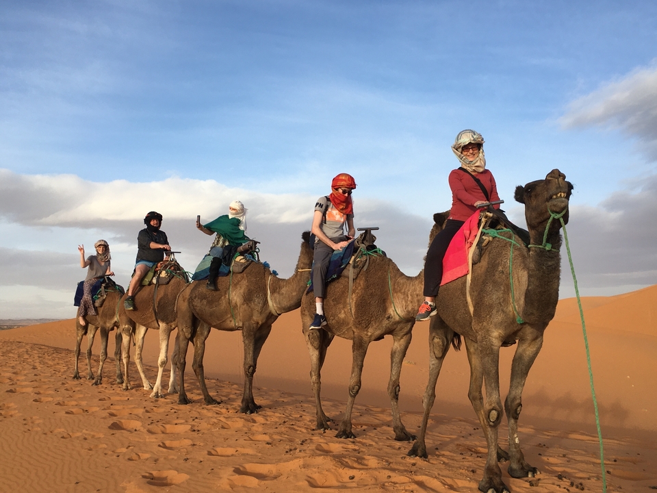 Des gens qui montent des chameaux dans un désert de sable.
