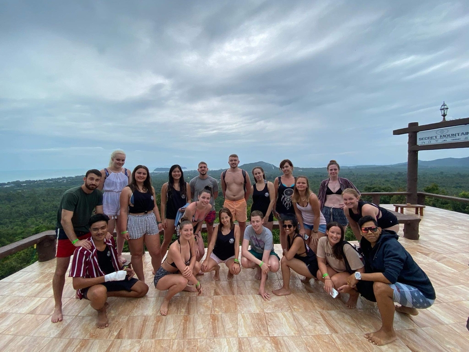 Group of people posing together on a terrace with a scenic backdrop.