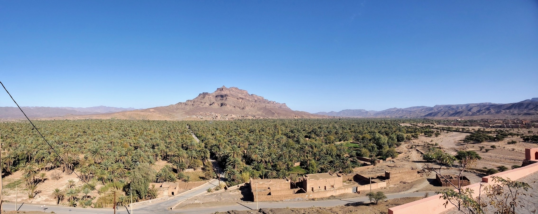 Paysage de village marocain avec palmiers et montagnes.