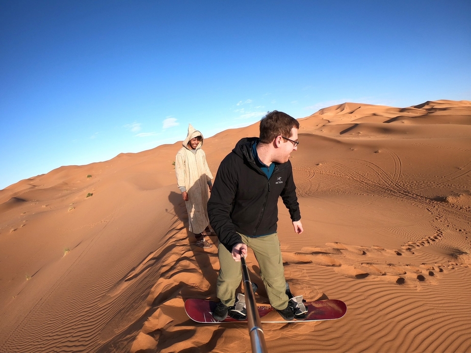 Personne marchant sur une dune de sable avec des traces dans le sable.