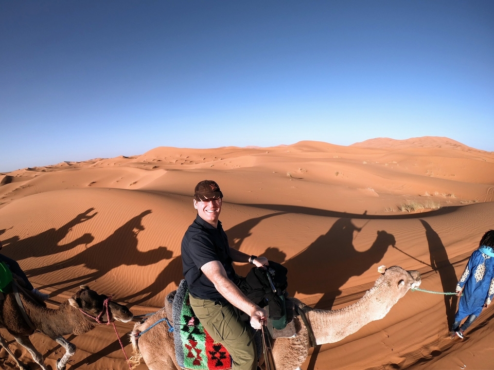 Personne montant un chameau dans le désert avec des ombres sur le sable.