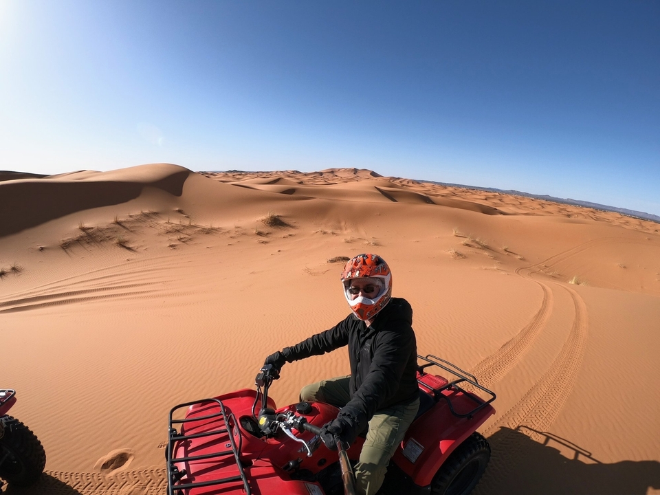 Personne sur un quad dans le désert avec des dunes de sable.