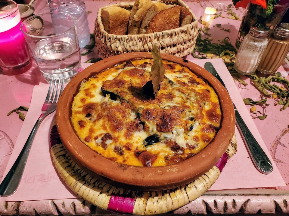 Gratin cuit dans un pot en terre cuite et garni de fromage.