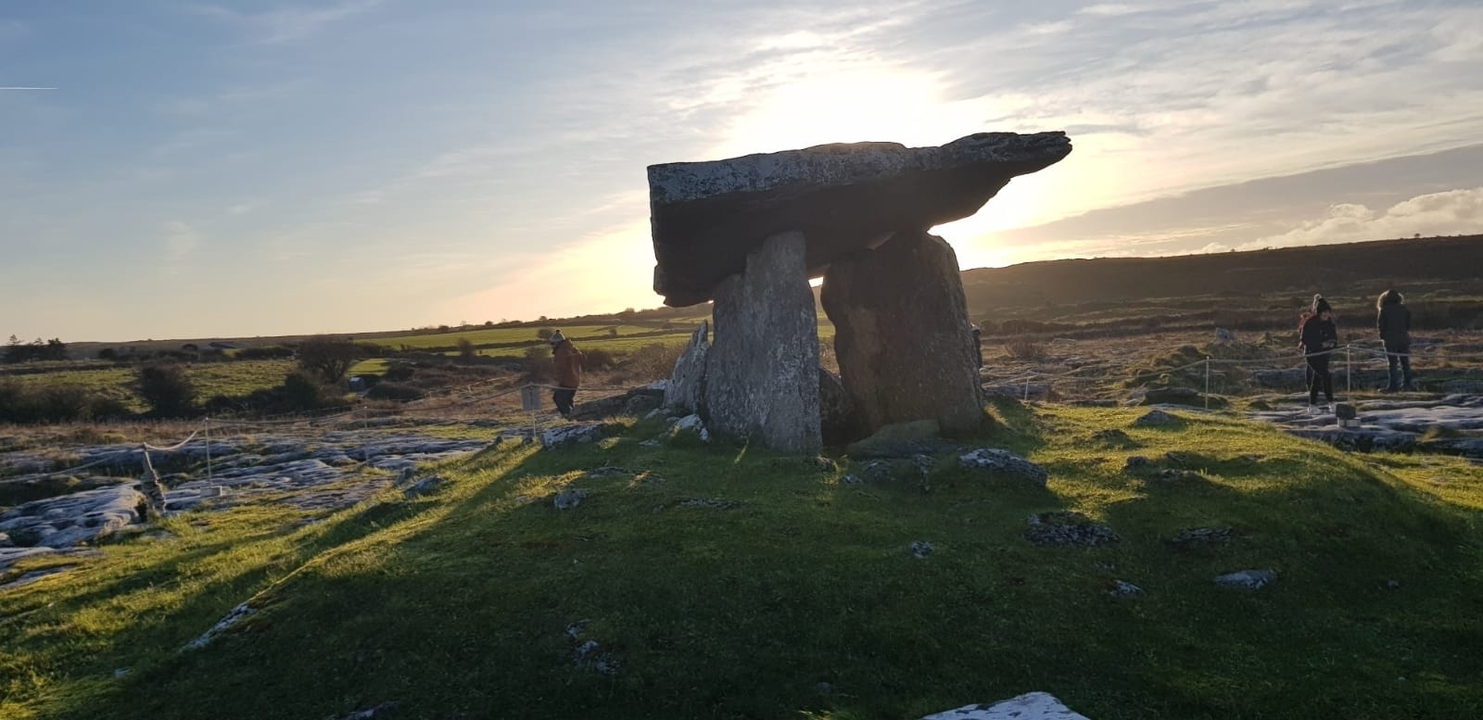 Ancien dolmen de pierre dans un champ au coucher du soleil.