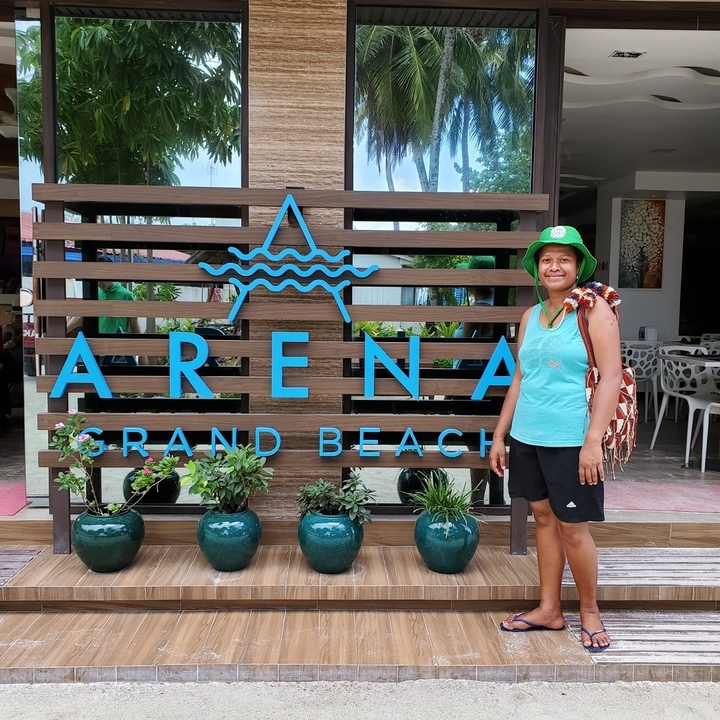 Femme posant devant un panneau « Arena Grand Beach ».