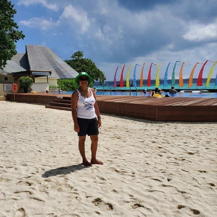 Femme debout sur une plage devant des drapeaux colorés.