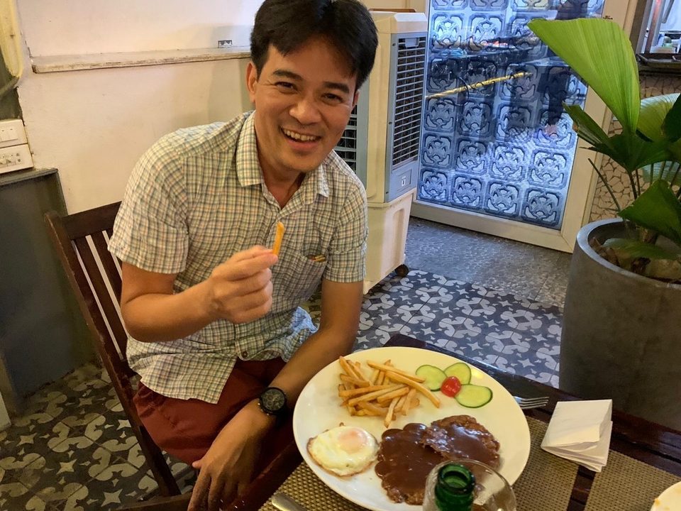 Un homme savourant un repas avec des frites dans un cadre chaleureux.