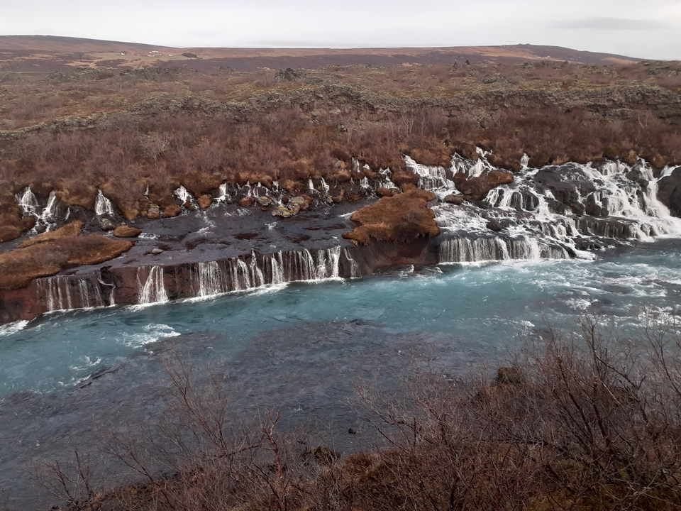 Río con pequeñas cascadas bordeado por follaje.