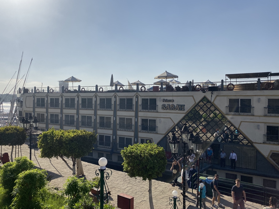Navire de croisière amarré au bord d'une rivière avec un ciel bleu.