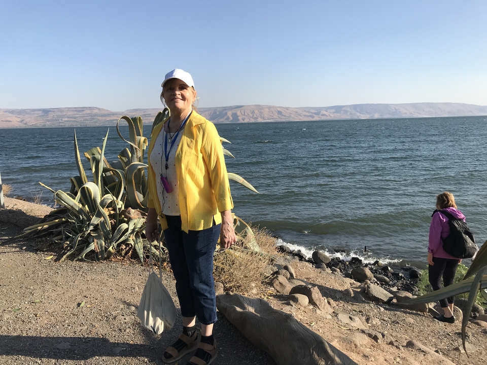 Personne debout au bord d'un lac avec des collines en arrière-plan.