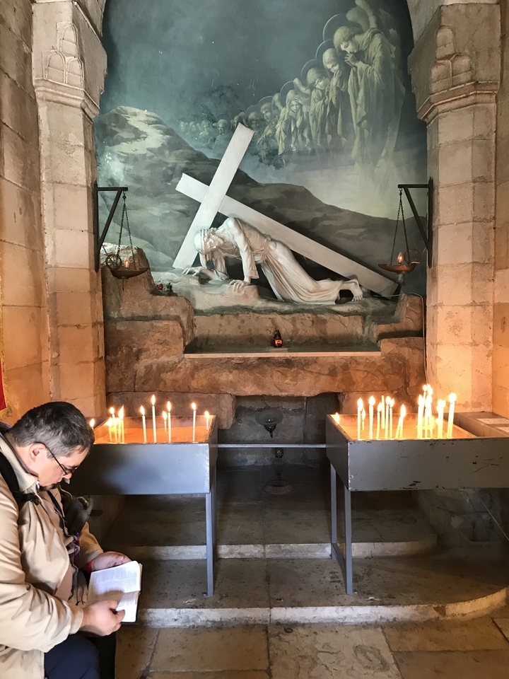 Site religieux avec des bougies allumées et une statue à l'intérieur d'un bâtiment en pierre.