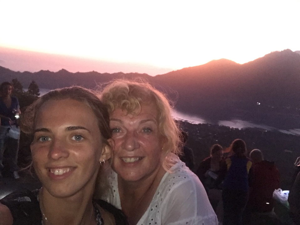 Deux personnes souriantes au coucher du soleil depuis le sommet d'une colline