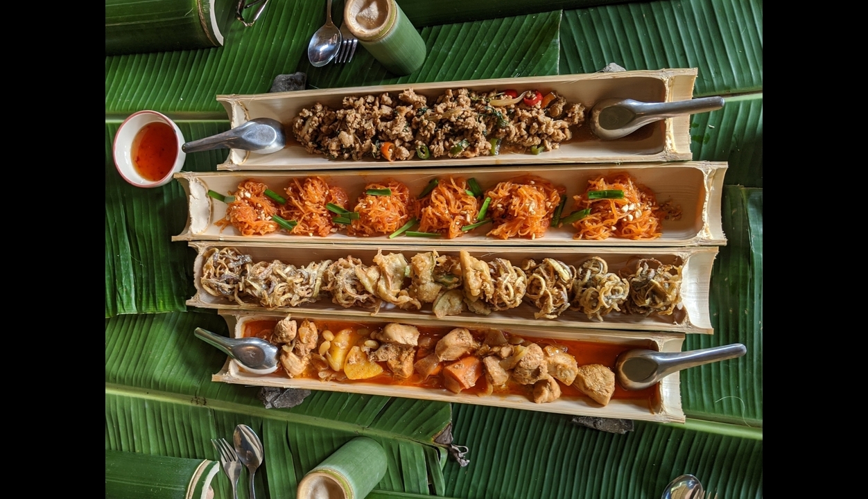 Cuisine thaïlandaise traditionnelle servie dans des plateaux en bambou allongés.
